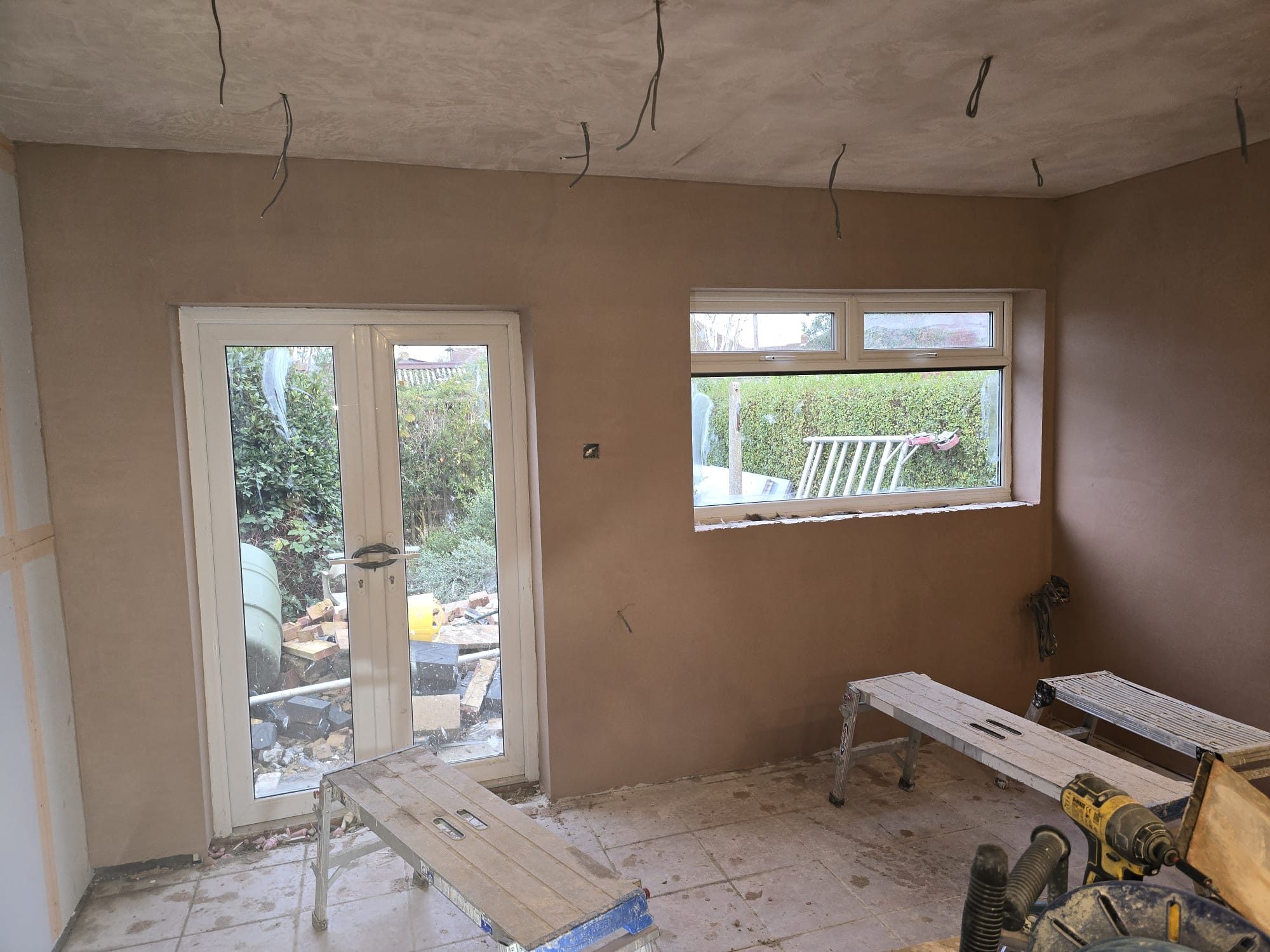 Freshly plastered house extension interior with French doors and new window