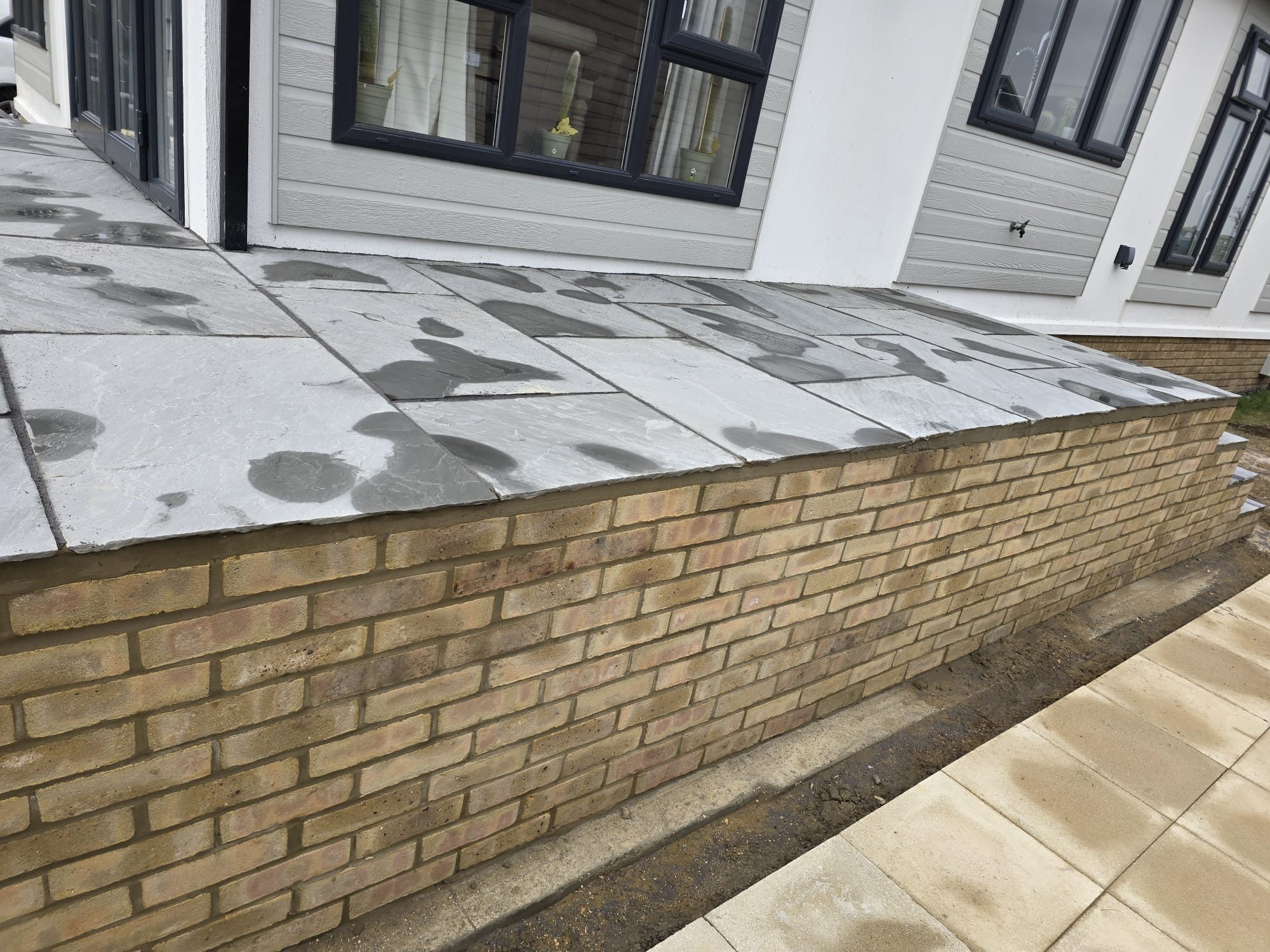 Indian sandstone patio laid on a new brick retaining wall