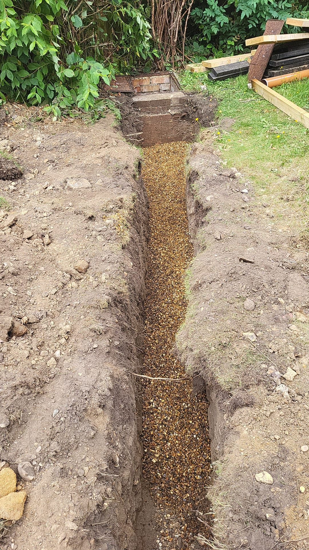 New drainage run bedded in gravel leading to a brick inspection chamber
